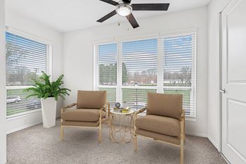 A room with two chairs and a table in front of a window with blinds. at Southpark Commons Apartment Homes, Charlotte, NC